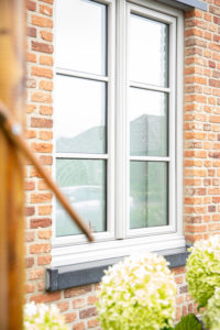 Klassiek Kömmerling raam met kruisverdeling in baksteen gevel