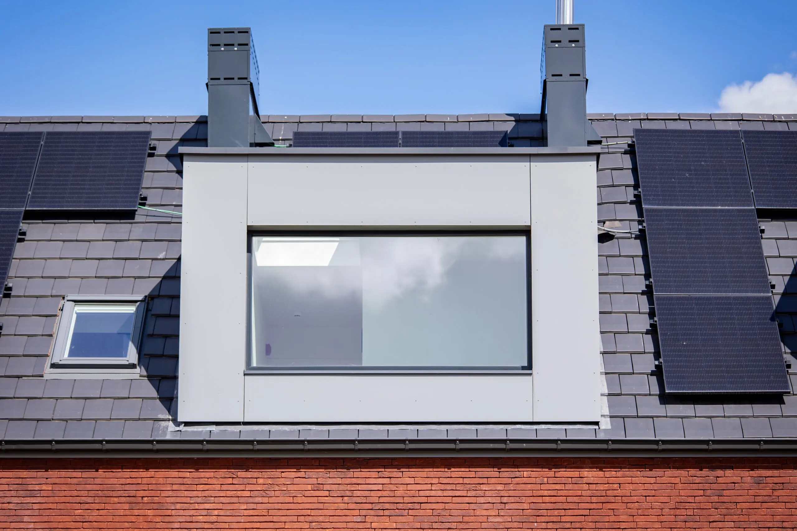 Breed raam in een dakkapel tussen zonnepanelen