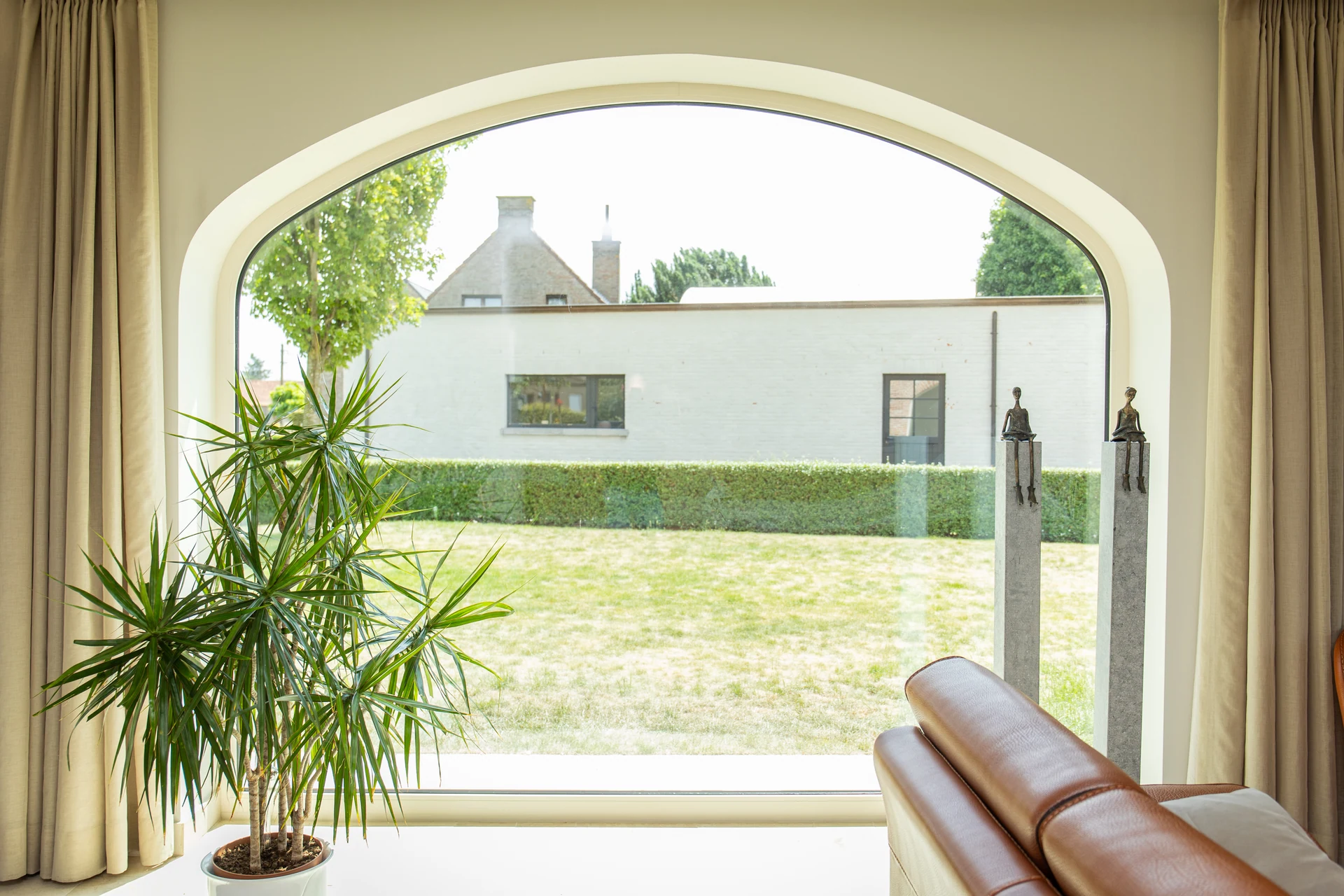 Woonkamer met een grote gebogen glaspartij en zicht op de tuin
