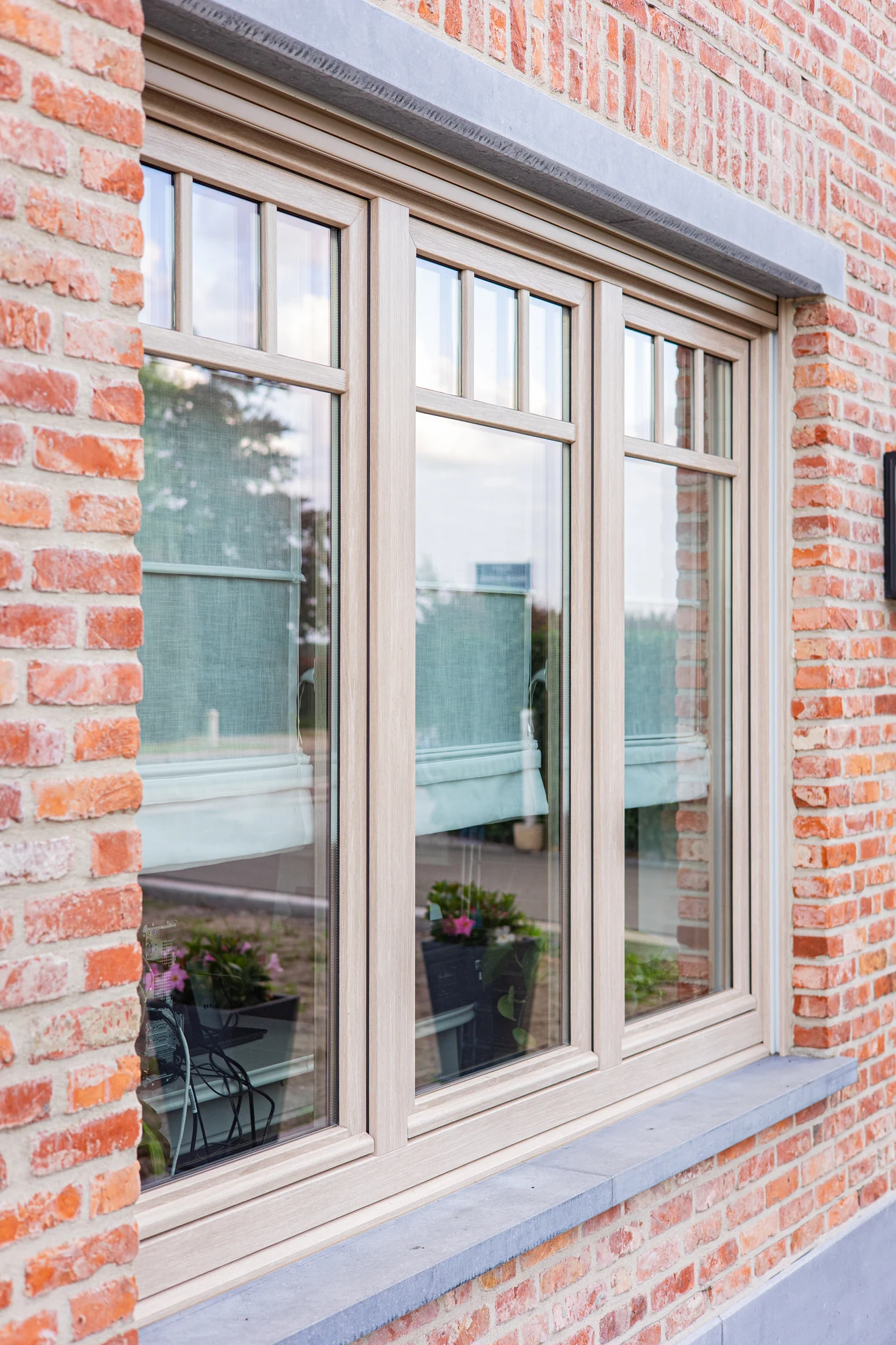 Detail van een raam met houtuitstraling en verticale roeden in het bovenlicht