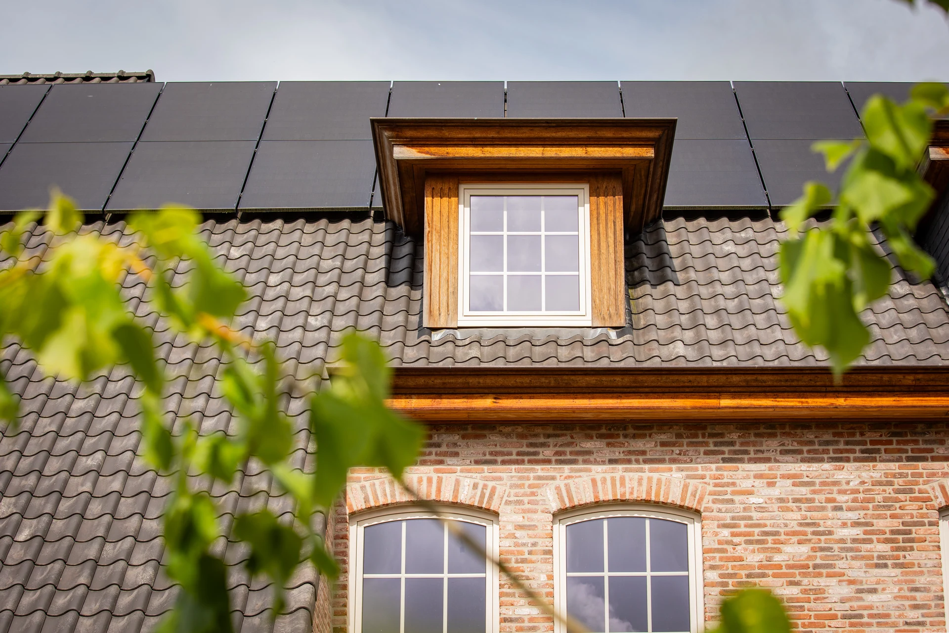 Dakkapel met een licht raam met roeden naast zonnepanelen