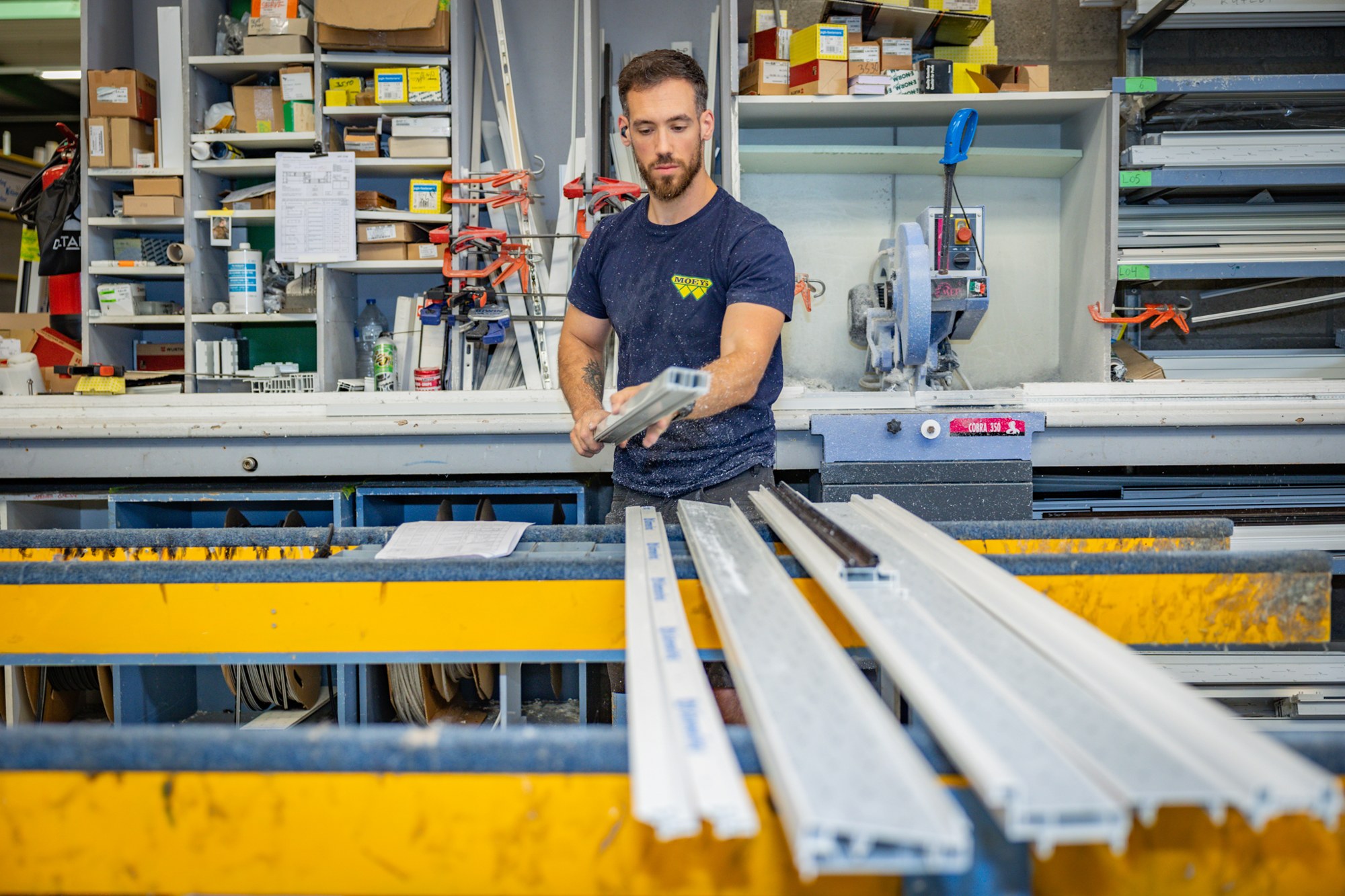 Vakman bewerkt een wit raamprofiel in de werkplaats